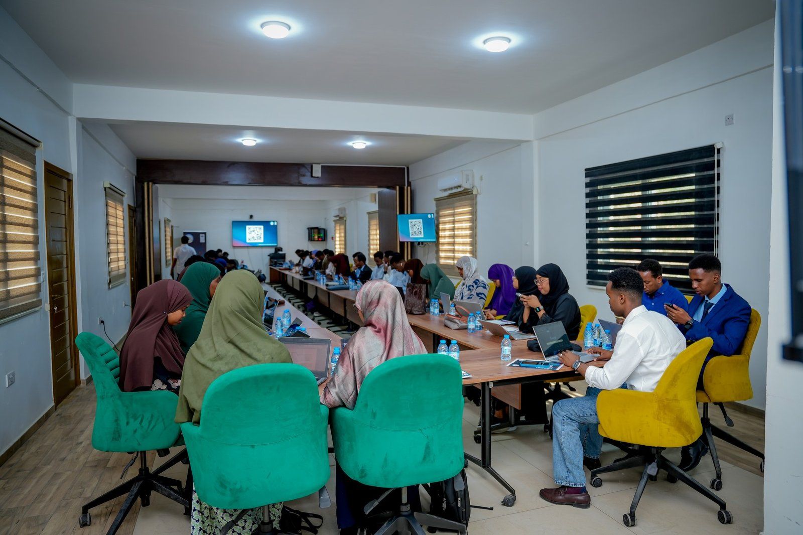 Participants working on laptops around a conference table during a training session